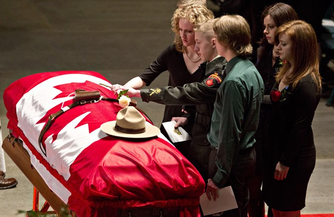 Matthew Wynn, son of slain RCMP Constable David Wynn places a flower on his dads casket during the funeral for Constable Wynn, in St. Albert, Alta., on Monday, January 26, 2015. 