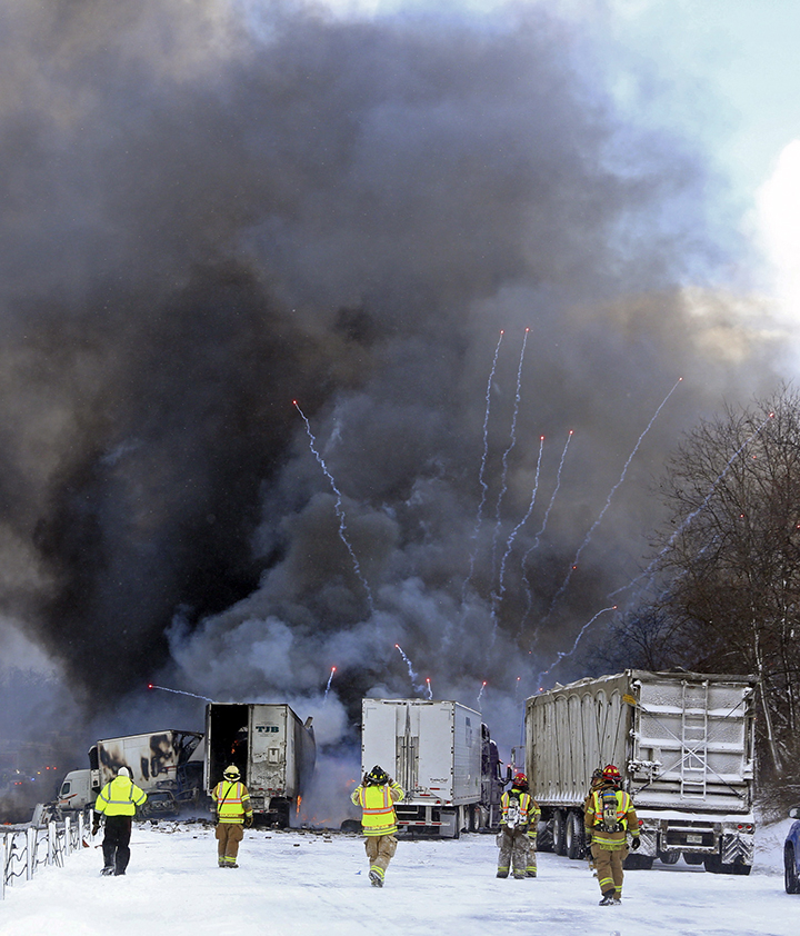 Emergency personnel watch as fireworks ignite at the scene of a fiery crash that closed both sides of Interstate 94, Friday, Jan. 9, 2015, between mile markers 88 and 92 in eastern Kalamazoo County, near Galesburg, Mich.