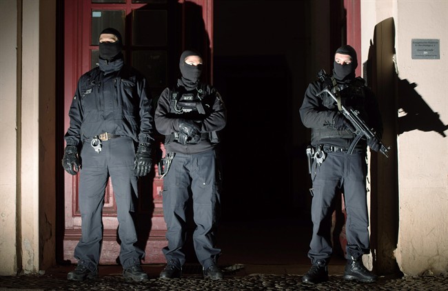 Special police force guards the entrance of a house in Berlin as police raids several residences in Berlin on suspicion of recruiting fighters and procuring equipment and funding for the so-called Islamic State terrorism group in Syria Friday morning Jan 16, 2015. (AP Photo/dpa, Lukas Schulze).