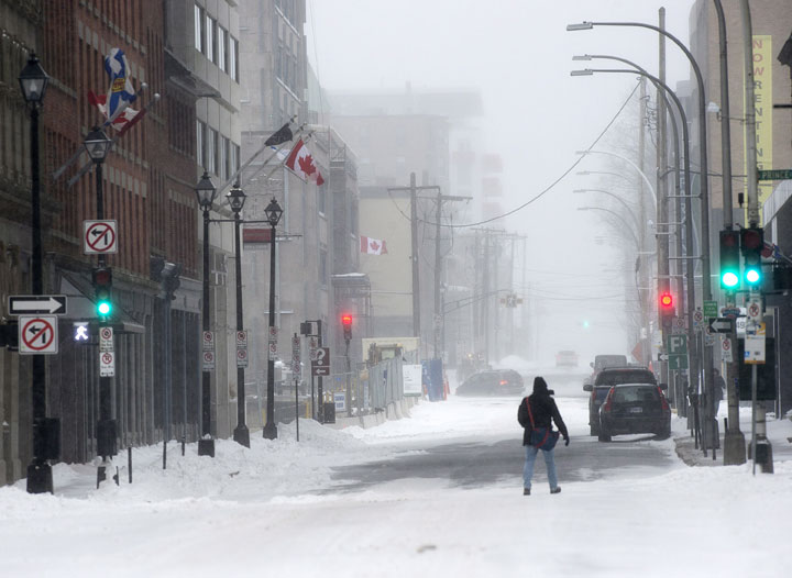 A pedestrian crosses a street as a major winter storm hits in Halifax on Tuesday, Jan. 27, 2015. 