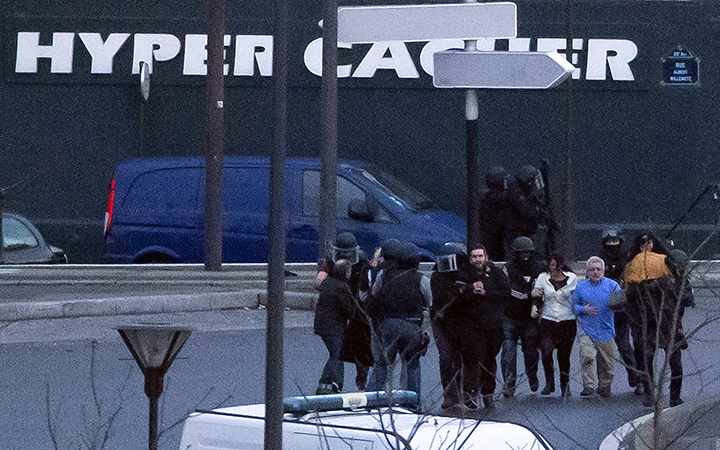 Security officers escort released hostages after they stormed a kosher market to end a hostage situation, Paris, Friday, Jan. 9, 2015.