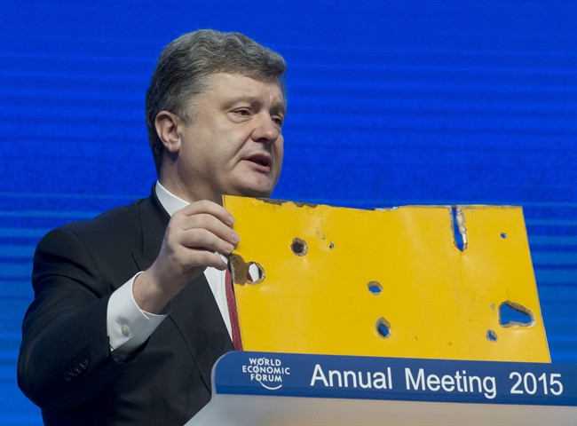 Ukrainian President Petro Poroshenko shows a piece of a Bus that was attacked recently during the panel "The Future of Ukraine" in Davos, Switzerland, Wednesday, Jan. 21, 2015.