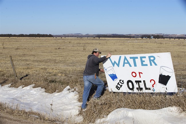 Land owner Jim Tarnick of Fullerton, Neb., who opposes the Keystone XL pipeline, hangs on to an anti-Keystone XL pipeline sign at the site where the planned pipeline is to go through his land, Friday, Jan. 16, 2015. 