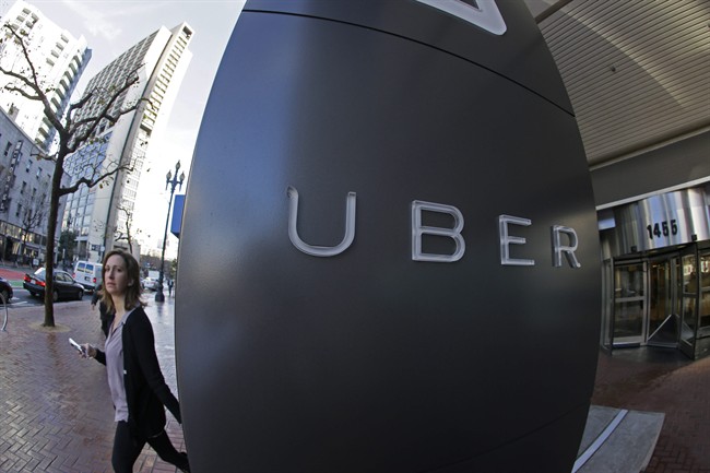 In this Tuesday, Dec. 16, 2014 photo, a woman leaves the headquarters of Uber in San Francisco. 