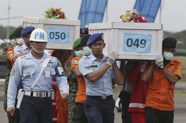 FILE - In this Monday, Jan. 19, 2015, file photo, members of the National Search and Rescue Agency carry coffins containing bodies of the victims aboard AirAsia Flight 8501 to transfer to Surabaya at the airport in Pangkalan Bun. (AP Photo/Achmad Ibrahim, File).