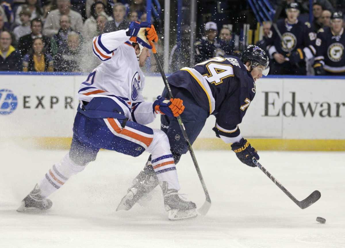 St. Louis Blues' T.J. Oshie (74) spins away from Edmonton Oilers' Nikita Nikitin (86) as he reaches for the loose puck in the second period of a NHL hockey game, Tuesday, Jan. 13, 2015 in St. Louis. 