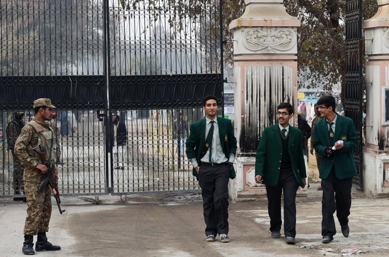 Pakistani soldiers stand guard as students leave the Army Public School after it was reopened following an attack there by Taliban militants in Peshawar on January 12, 2015.