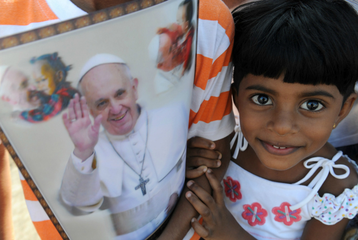 A young Sri Lankan holds paraphernalia bearing the portrait of Pope Francis as she waits for his arrival in Colombo on January 13, 2015. Pope Francis urged respect for human rights in Sri Lanka as he began a two-nation Asia tour on the island, bearing a message of peace and reconciliation after a long civil war. 