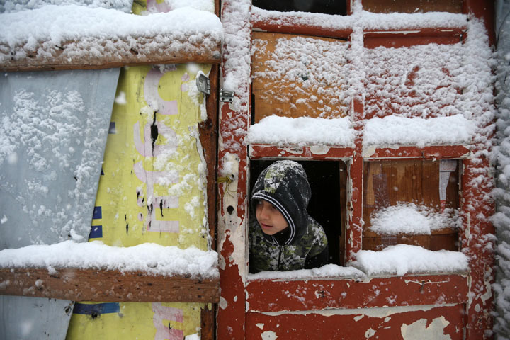 A Syrian boy looks out through his tent door covered in snow at a refugee camp in Deir Zannoun village, in the Bekaa valley, east Lebanon, Wednesday, Jan. 7, 2015. 
