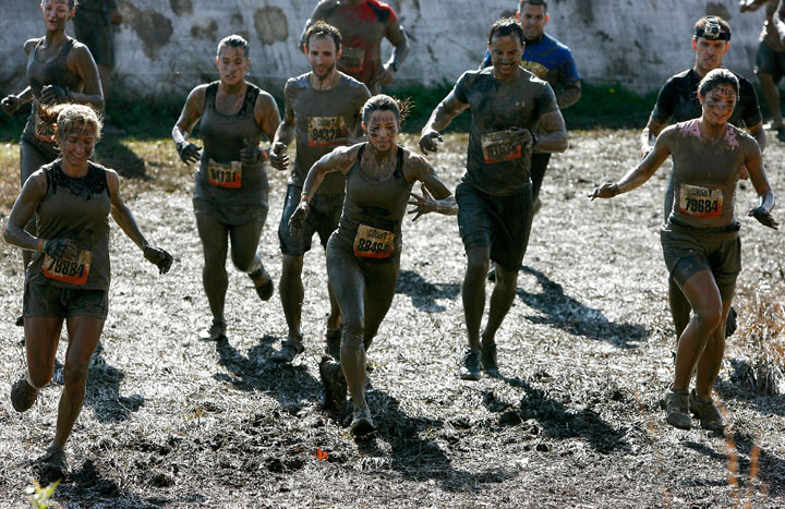 Participants run through the Mud Mile obstacle during Tough Mudder - Tri-State at Raceway Park on October 20, 2012 in Englishtown, New Jersey.  