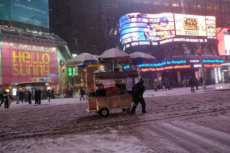 A vendor steers his cart through a street in New York's Times Square during a snow storm on January 26, 2015. 