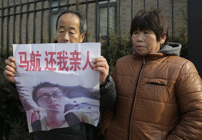 A couple whose son aboard Malaysia Airlines Flight 370 that went missing on March 8, 2014, show off a poster featuring a photo of their son as they hold a protest to demand the Malaysian government to keep searching the missing plane near Malaysian Embassy in Beijing Thursday, Jan. 29, 2015. 