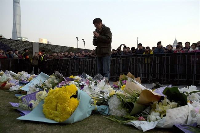 In this Thursday, Jan. 1, 2015 file photo, a man prays after laying flowers at the site of a New Year’s Eve deadly stampede in Shanghai, China.