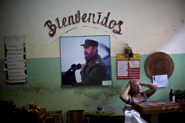 FILE - In this Dec. 26, 2014 file photo, a photograph of Fidel Castro hangs under the Spanish word "Welcome" on the wall at a state-run food market in Havana, Cuba.