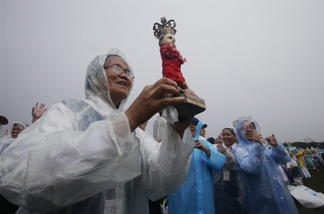 A nun holds the statue of the infant Jesus in the rain as Pope Francis celebrates his final Mass in Manila, Philippines, Sunday, Jan. 18, 2015.