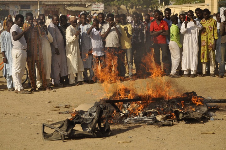 In this file photo taken Friday, Nov. 28, 2014, people gather at the site of a bomb explosion in an area known to be  targeted by the militant group Boko Haram  in Kano, Nigeria. 