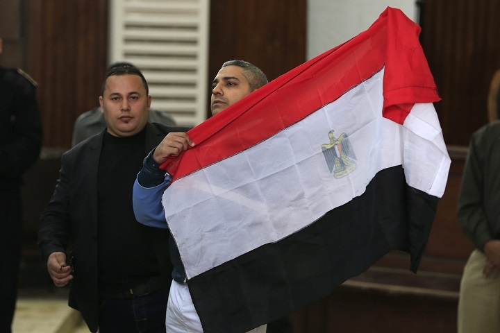 Mohamed Fahmy, a Canadian journalist of Al-Jazeera English, holds up an Egyptian flag after a retrial at a courthouse near Tora prison in Cairo, Egypt, Thursday, Feb. 12, 2015. 