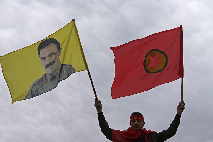 A Kurdish man waves a flag of the Kurdistan Workers' Party, known as PKK, right, and a flag with a portrait of the jailed Turkish Kurdish guerrilla leader Abdullah Ocalan, left, during a demonstration demanding his release, in Beirut, Lebanon, Sunday, Feb. 15, 2015.