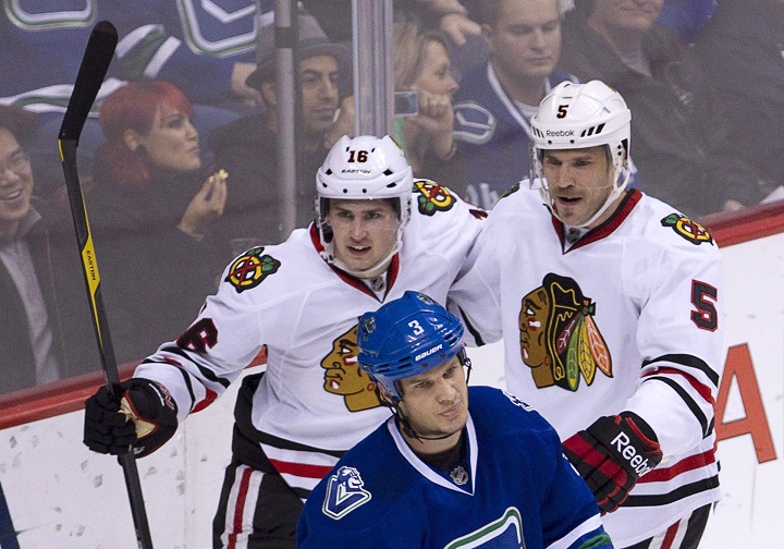 Chicago Blackhawks center Marcus Kruger (16) and Steve Montador (5) celebrate teammate Andrew Brunette's goal during second period as Vancouver Canucks defenseman Kevin Bieksa (3) looks on during NHL hockey action at Rogers Arena in Vancouver, B.C. Wednesday, Nov. 16, 2011.