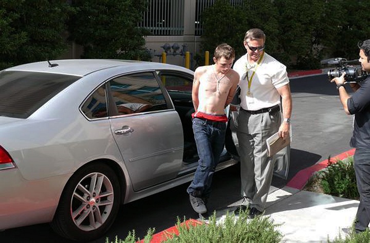 In this photo released by the Las Vegas Metropolitan Police Department, an unidentified police official leads a shirtless suspect in the road-rage killing of a Las Vegas mother from a car to police headquarters for questioning in Las Vegas, Thursday, Feb. 19, 2015.