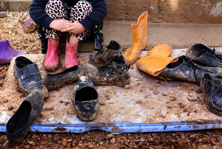 A displaced Iraqi girl from the Yazidi community, who fled violence between Islamic State (IS) group jihadists and Peshmerga fighters in the northern Iraqi town of Sinjar, sits near muddy shoes at Dawodiya camp for internally displaced people in the Kurdish city of Dohuk, in Iraq's northern autonomous Kurdistan region, on January 14, 2015. 