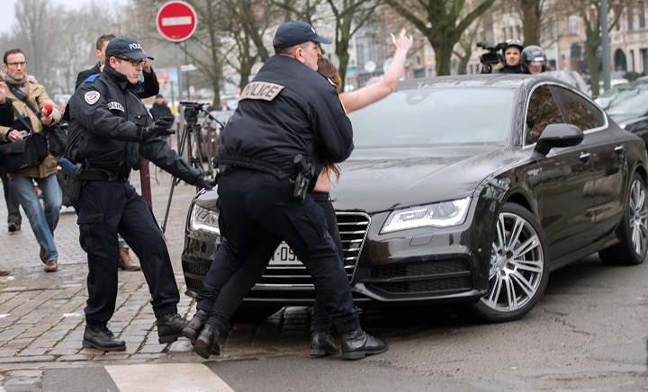 Police detain a topless Femen activist who jumped on the car carrying former IMF chief Dominique Strauss-Kahn (not seen) upon his arrival for his trial in Lille, northern France, on February 10, 2015.