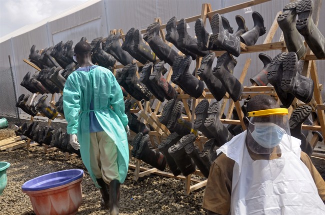 Health care workers walk past boots that were washed to prevent the spread of the Ebola virus inside a USAID, funded Ebola clinic in Monrovia, Liberia, Friday, Jan. 30, 2015.