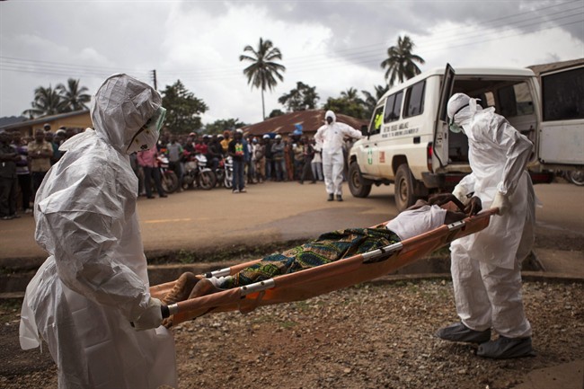 In this Wednesday, Sept. 24, 2014 file photo, health care workers move a man suspected of suffering from the Ebola virus in Kenema, Sierra Leone. 