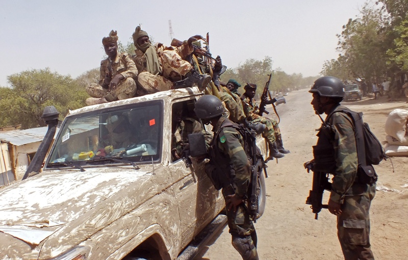 In this photo taken on Thursday, Feb. 19, 2015, Chadian soldiers on top of a truck, left, speak to Cameroon soldiers, right, standing next to the truck, on the border between Cameroon and Nigeria as they form part of the force to combat regional Islamic extremists force's including Boko Haram, near the town of Gambarou, Nigeria.