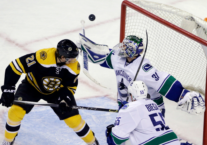 Vancouver Canucks goalie Eddie Lack (31) keeps an eye on the rebounding puck as Boston Bruins left wing Loui Eriksson (21) watches along with Canucks defenseman Alex Biega (55) during the third period of an NHL hockey game in Boston, Tuesday, Feb. 24, 2015. 