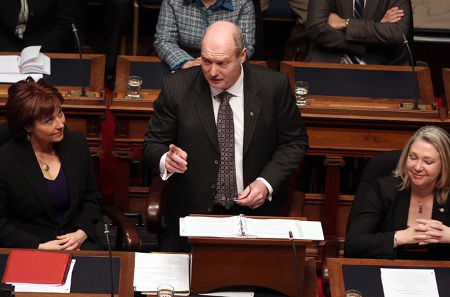 B.C. Finance Minister Mike de Jong, tables the budget in the Legislative Assembly in Victoria, B.C., Tuesday February 17, 2015 as Premier Christy Clark (left) looks on.