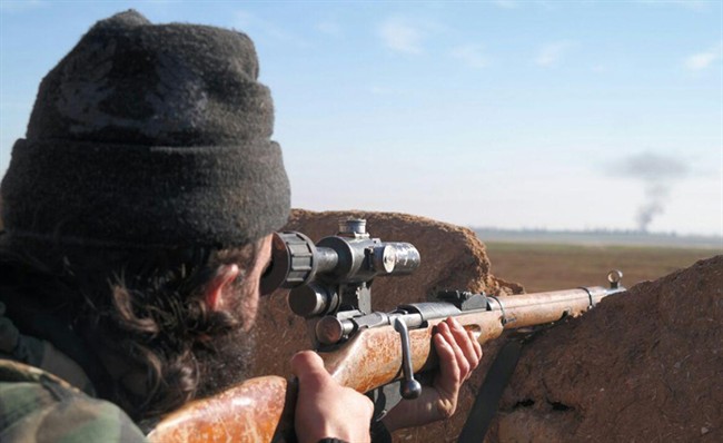 FILE - In this image posted on a militant social media account by the Al-Baraka division of the Islamic State group on Tuesday, Feb. 24, 2015, a militant fighter aims a sniper rifle during during fighting in Tal Tamr, Hassakeh province, Syria. 