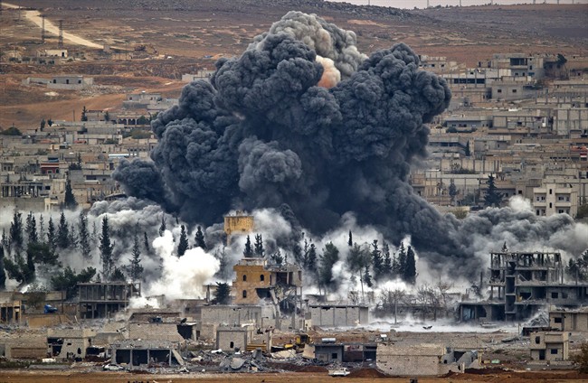 In this Nov. 17, 2014 file photo, smoke rises from the Syrian city of Kobani, following an airstrike by the U.S.-led coalition, seen from a hilltop outside Suruc, on the Turkey-Syria border.