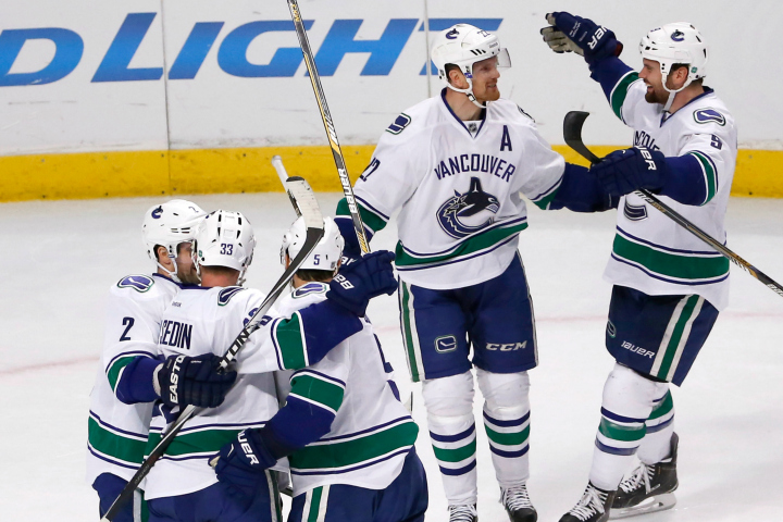 The Vancouver Canucks' celebrate their 5-4 win over the Chicago Blackhawks after Daniel Sedin's, top left, goal during an overtime period of an NHL hockey game Wednesday, Feb. 11, 2015.