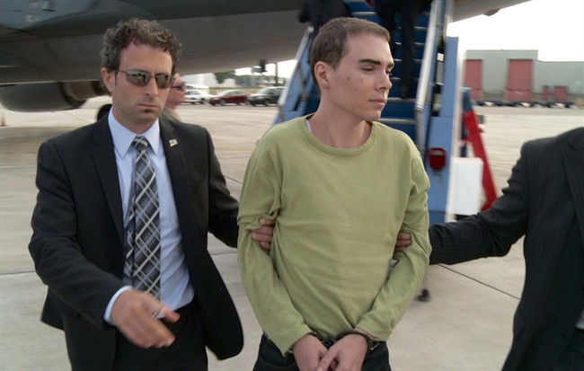 Luka Rocco Magnotta is taken by police from a Canadian military plane to a waiting van on Monday, June 18, 2012 in Mirabel, Que.