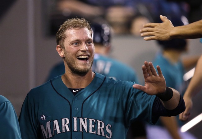 Mariners' Michael Saunders smiles as he is congratulated in the dugout on his home run against the Minnesota Twins in the seventh inning of a baseball game Monday, July 7, 2014, in Seattle.