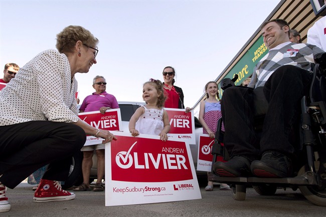 Ontario Liberal Leader Kathleen Wynne greets two-year-old Ella Prosperi as she arrives at a campaign event for candidate Andrew Olivier (right) in Sudbury, Ont. on Tuesday May 27, 2014, 2014. Elections Ontario has come to the ``unprecedented'' conclusion that the actions of two Liberals, including the premier's deputy chief of staff, constitute an ``apparent contravention'' of a bribery section of the Election Act.