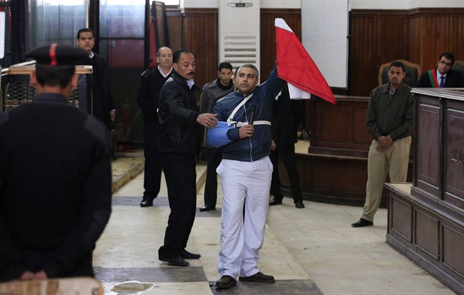 Canadian Al-Jazeera journalist Mohamed Fahmy holds up an Egyptian flag in a courthouse near Tora prison in Cairo, Egypt on Feb. 12, 2015.