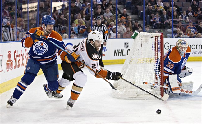 Anaheim Ducks' Kyle Palmieri (21) and Edmonton Oilers' Matt Hendricks (23) battle for the puck as goalie Ben Scrivens (30) keeps an eye on the play during first period NHL hockey action in Edmonton, Alta., on Saturday February 21, 2015.