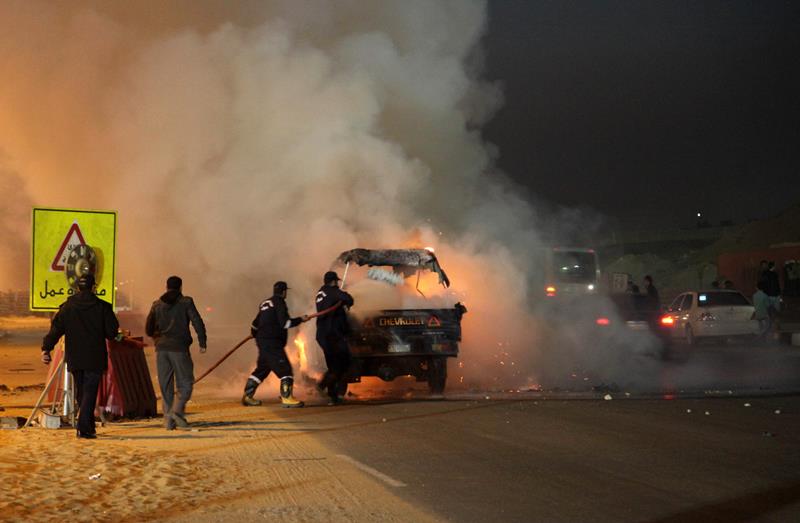 Egyptian firefighters extinguish fire from a vehicle outside a sports stadium in a Cairo's northeast district, on February 8, 2015 during clashes between supporters of Zamalek football club and security forces. 