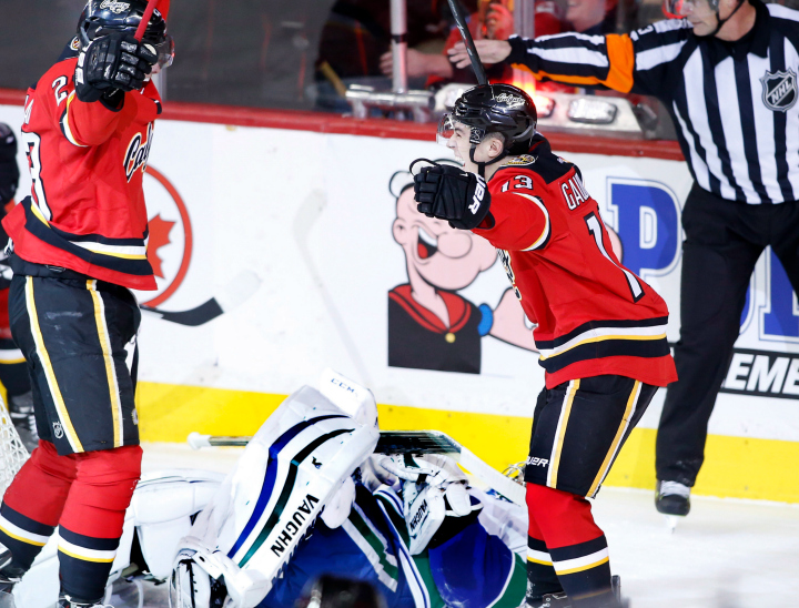 Calgary Flames' Sean Monahan, left, celebrates his goal with Johnny Gaudreau, right, as Vancouver Canucks' Ryan Miller lays on the ice during second period NHL action in Calgary, Alta., Sat., Feb. 14, 2015.