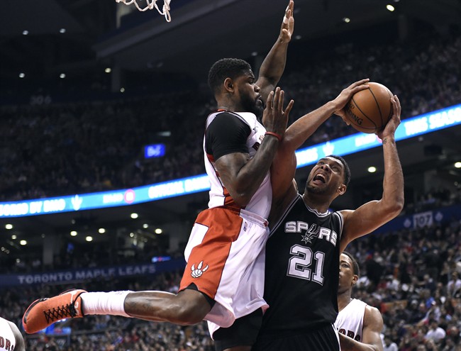 San Antonio Spurs' Tim Duncan, right, attempts a shot as Toronto Raptors' Amir Johnson defends during first half NBA basketball action in Toronto on Sunday, Feb. 8, 2015.