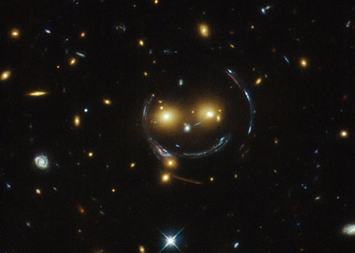 A galaxy cluster appears to be smiling at us in this new Hubble image.
