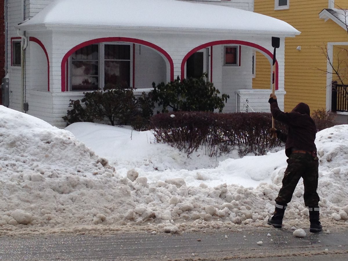 A man uses a pickaxe while attempting to clear his driveway.