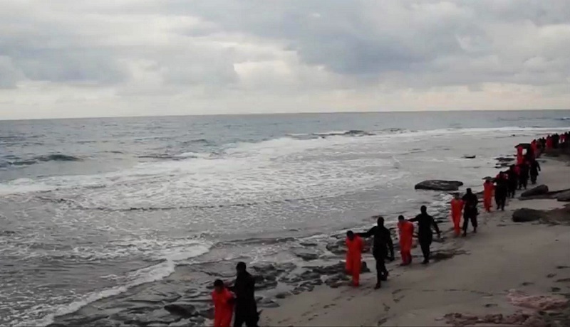 This image made from a video released Sunday Feb. 15, 2015 by militants in Libya claiming loyalty to the Islamic State group purportedly shows Egyptian Coptic Christians in orange jumpsuits being led along a beach, each accompanied by a masked militant.