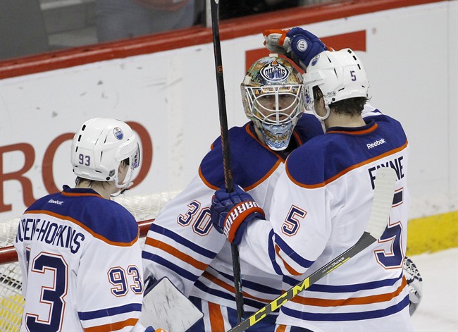 Edmonton Oilers defenseman Mark Fayne (5) and center Ryan Nugent-Hopkins (93) celebrate with goalie Ben Scrivens (30) after the Oilers defeated the Minnesota Wild 2-1 in an NHL hockey game in St. Paul, Minn., Tuesday, Feb. 24, 2015. 
