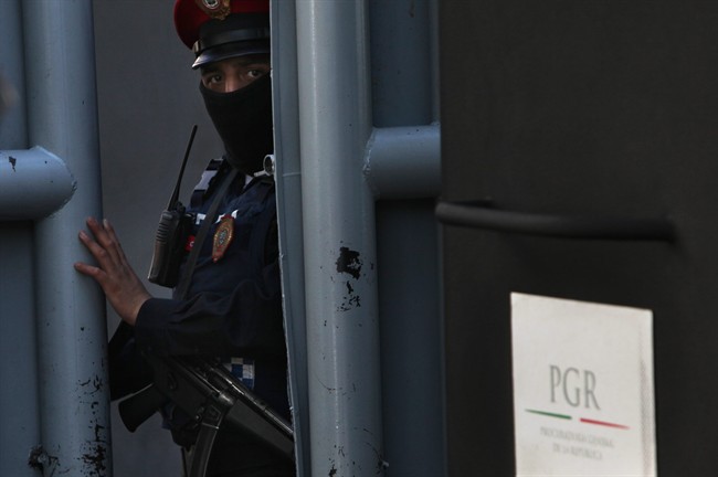 A masked federal police officer stands guard as part of increased security at the organized-crime division of Mexico's Attorney General Office in Mexico City, Friday, Feb. 27, 2015.