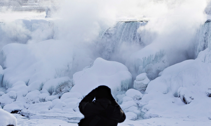 A man photographs ice masses formed around the American Falls in Niagara Falls, Ontario.