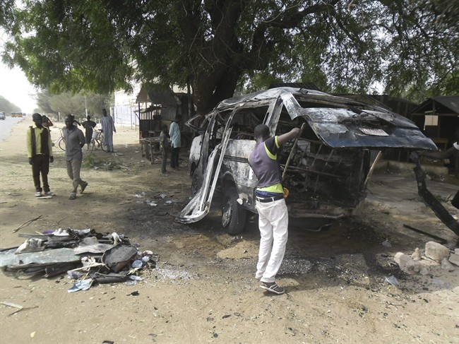 A man inspects a bus following an explosion on the street in Potiskum, Nigeria. Tuesday, Feb. 24, 2015.
