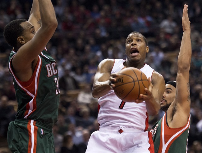 Toronto Raptors guard Kyle Lowry, centre, drives to the net past Milwaukee Bucks forward John Henson, left, and guard Jerryd Bayless, right, during first half NBA basketball action in Toronto on Monday, February 2, 2015. 